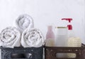 Box with rolled white dry towels and box with bottles of shampoo, hair conditioner, liquid soap and shower sponge against white wa Royalty Free Stock Photo