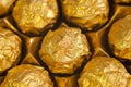 Box of round candies wrapped into golden foil. Macro shot.