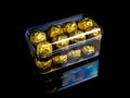 A box of round chocolates in a golden wrapper on a black background Royalty Free Stock Photo