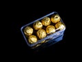 A box of round chocolates in a golden wrapper on a black background Royalty Free Stock Photo