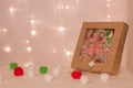 A box with a set of felt toys made of pigs, dwarfs, stars and handmade cookies stands against the background of Christmas lights