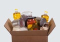 Box with a set of products from cereals, rice, vegetable oil, legumes and canned vegetables on a light background. Help, charity. Royalty Free Stock Photo