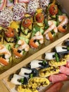 Box with small sandwiches with cold cuts, grilled vegetables, cheese and seafood. Charcuterie boards to order Royalty Free Stock Photo