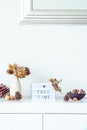 Box with text FALL TIME, dried flowers, thorns in vase, pine cones, other natural decor on white wall background. Eco, simple home