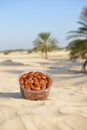 Box of Tunisian dates on desert sand with palm trees in background Royalty Free Stock Photo