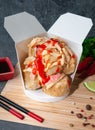 Box for wok. With pieces of fried tofu, crab meat, squid. And hot chili sauce. The wok box is cut. Standing on a mat next to Royalty Free Stock Photo