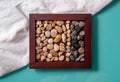 The box is wooden with sea pebbles, laid out on a light and dark strip.