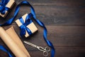 Box wrapped in brown paper and tied with a blue silk ribbon with a bow, gift on a brown wooden background Royalty Free Stock Photo