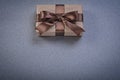 Boxed present in brown wrapping paper on grey background directl Royalty Free Stock Photo