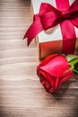 Boxed present with tied bow expanded rose on wooden board