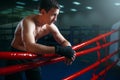 Boxer in black bandages poses on ring ropes