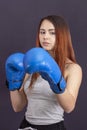 Boxer girl in blue boxing gloves in a gray t-shirt in rack