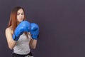 Boxer girl in blue boxing gloves in a gray t-shirt in rack