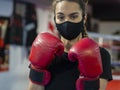 Boxer girl wearing a mask and red boxing gloves in a gym. Royalty Free Stock Photo