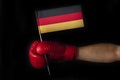 Boxer hand holds flag of Germany. Boxing glove with the Germanian flag. Black background