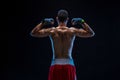 A boxer in his shorts stands with his back on black background. Handsome young bodybuilder with toned body posing Royalty Free Stock Photo