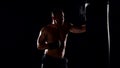 Boxer man during boxing hiting heavy bag at