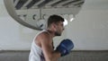 Boxer is on a training outdoors on the background of gray concrete walls with circular holes.