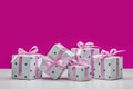 Boxes with gifts on a pink background. Stylish modern gifts in white paper with asterisks, decorated with pink satin ribbon with b