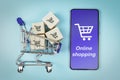 Boxes in a shopping cart and smartphone on blue background. Concept: online shopping, e commerce and delivery of goods Royalty Free Stock Photo