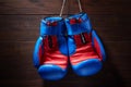 Boxing blue and red gloves hanging from ropes on a wooden background.