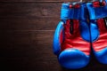 Boxing blue and red gloves hanging from ropes on a wooden background.