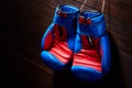 Boxing blue and red gloves hanging from ropes on a wooden background. Royalty Free Stock Photo