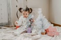 Boxing day. Little baby girl and mom unpack pink gift boxes near the Christmas tree. The kid touches bright Christmas-tree Royalty Free Stock Photo