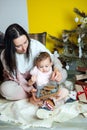 Boxing day and unpacking Christmas gift boxes. Cute Little baby toddler girl and mom unpack gift boxes near the Royalty Free Stock Photo