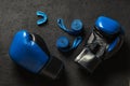 Boxing gloves with mouthguard and blue boxing bandages on a black background