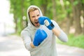 Boxing training endurance. Man athlete concentrated face with sport gloves practicing boxing nature background. Boxer