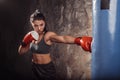 Boxing. Woman boxer in gloves exercise with punching bag practising kick side view Royalty Free Stock Photo