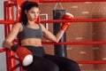 Boxing. Woman boxer in gloves sitting in the corner of ring leaning back tired Royalty Free Stock Photo