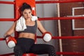 Boxing. Woman boxer with towel on neck in gloves sitting in the corner of ring looking forward curious Royalty Free Stock Photo
