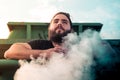 Boy with abundant beard, thoughtful looking towards the horizon. View from below with smoke