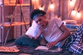 Boy of African descent reclining on the bed with a book and yawning.