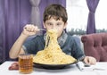 Boy is appetizing eats a large Italian spaghetti