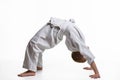 Boy athlete makes a bridge at the warm-up of the judo section