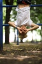 The boy athlete on the sports ground in the park caught his feet on the stairs and hangs upside down shows different gestures with