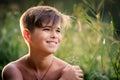 Boy of athletic build walks among tall grass and flowers in the park