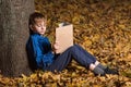 Boy in autumn forest with book. Child fell asleep in woods with book in hand