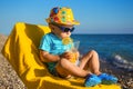 Boy baby in sun glasses and hat on beach drinks juice