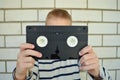 A boy on the background of a brick wall is holding a videotape, a very popular technology of the 90s Royalty Free Stock Photo