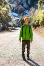 boy with a backpack in the forest. The child is standing in the middle of the road in the forest