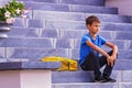 Boy with backpack sitting on the stairs outdoors