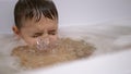 Boy Bathes in Foam Water in Bathtub, Submerges Under Water, Blows Bubbles Close-up.