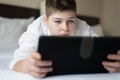 Boy in bathrobe Uses tablet in hotel room