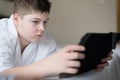 Boy in bathrobe Uses tablet in hotel room