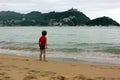 Boy at the beach looking at the water in rainy weather