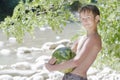 Boy in beach shade holding big green watermelon